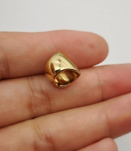 Close-up of minimalist gold geometric ear cuff held by fingers for scale and detail