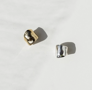 Macro view of minimalist irregular gold and silver ear cuffs with hammered metal texture