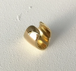 Detailed close-up of a polished gold minimalist U-shaped ear cuff on a white background