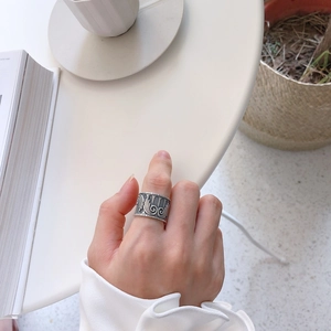 Close-up of vintage wide silver ring with intricate embossed angel wing patterns