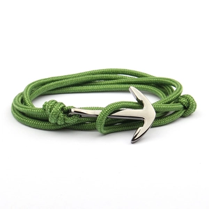 Detail of green nylon cord bracelet with polished silver anchor clasp on white background