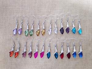 Detailed display of 12 teardrop crystal earrings in various vibrant colors on linen