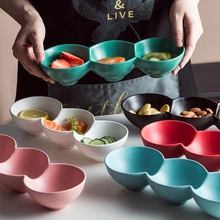 Three-grid ceramic bowl in deep green held by hand showing divided compartments for food
