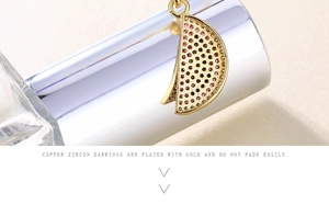 Detail of gold-plated copper watermelon earrings with red zircon stones on metal