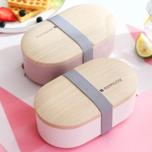 Detail of pink and white oval bento boxes with wooden texture lids and elastic straps