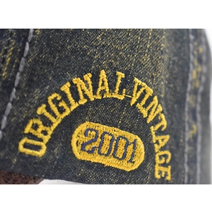 Detail of vintage 2001 embroidery on washed navy denim baseball cap fabric