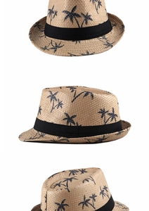Detail view of straw sun hat with black palm tree patterns and decorative black ribbon