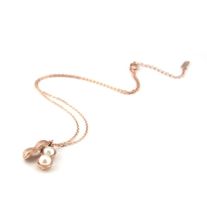 Detail shot of a rose gold peanut pendant with two small white pearls on a titanium chain