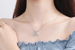 Detail shot of a silver letter K pendant necklace with pave crystals on female neck