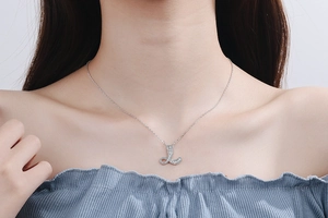 Close-up of diamond-encrusted letter L necklace pendant on a female collarbone