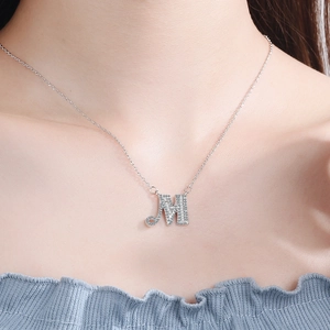 Detail view of silver necklace with letter M pendant featuring pavé stones and thin chain