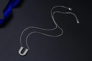 Detail of S925 silver letter U pendant with sparkling baguette zircons and hallmark