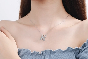 Detail shot of a silver letter R pendant necklace with sparkling zircons on a model