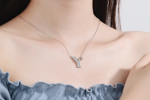 Close-up of a silver letter Y necklace with sparkling zircon pavé on a female model