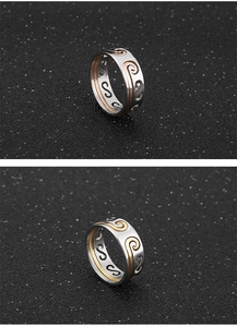 Detail of two-tone filigree rings with ornate scroll patterns and hollow S-shaped structure