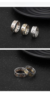 Macro shot of stacking rings with ornate cloud engravings in gold and silver finish