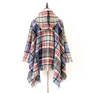 Dettaglio del poncho a quadri con cappuccio e nappe decorative sull'orlo inferiore