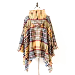 Dettaglio del poncho con cappuccio a quadri con frange in tartan giallo, rosso e blu
