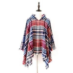 Dettaglio di un poncho a quadri rossi e blu con trama lanosa e bordi con frange