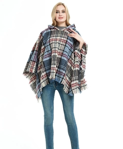 Poncho con cappuccio a quadri e frange blu, rosse e nere indossato da modella