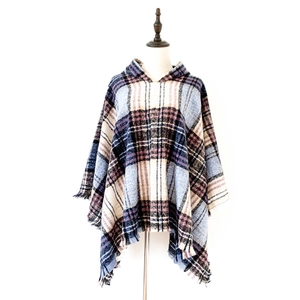 Dettaglio del poncho con cappuccio a quadri in tessuto blu e marrone con orlo a frange