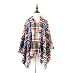Dettaglio di un poncho con cappuccio a quadri blu e beige con tessuto morbido e frange