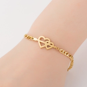Detail of interlocking twin hearts gold bracelet on wrist with elegant titanium steel finish