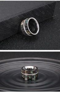 Macro detail of wide titanium ring with rainbow abalone shell inlay and pavé crystals