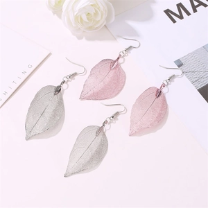 Detailed close-up of vintage hollow leaf earrings in silver and purple on floral decor