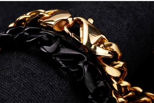 Macro shot of gold and black two-tone Cuban link bracelet featuring a secure metal clasp