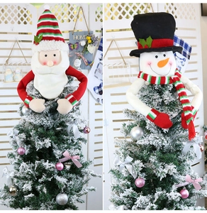 Detail of felt Santa and Snowman tree toppers with long arms hugging a snowy Christmas tree
