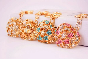 Close-up of four gold heart-shaped hollow keychains with colorful rhinestones in macro detail