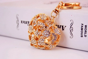 Close-up of golden hollow heart keychain with star, moon motifs and sparkling rhinestones
