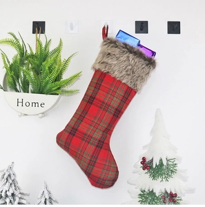 Close-up of red plaid Christmas stocking with faux fur trim hanging on a white hook