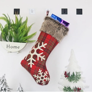 Détail d'une chaussette de Noël à carreaux rouges et verts avec flocons et fausse fourrure