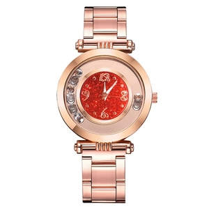 Close-up of rose gold watch with sparkling red dial and floating rhinestones