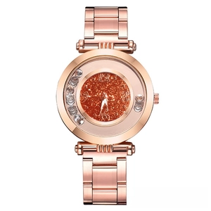 Detail of rose gold watch featuring sparkling orange dial and rhinestone encrusted case