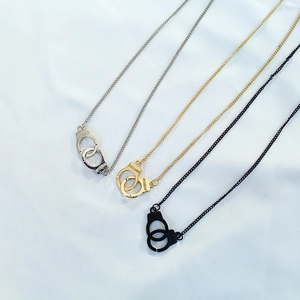 Close-up of handcuff pendants in silver, gold, and black with Freedom engraving