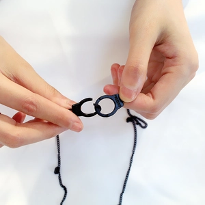 Detail of black handcuff pendant with FREEDOM engraving on a minimalist chain necklace
