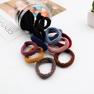 Macro shot of colorful ribbed elastic hair ties in a glass jar on a white desk