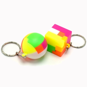 Detail of colorful puzzle ball and cube keychains with silver rings on white backdrop