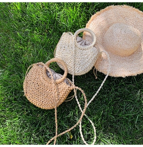 Close-up detail of the woven straw beach bag featuring round handle and fabric lining.