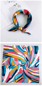 Detail of silk scarf with geometric blocks in pink and blue, tied as a bow and laid flat