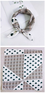 Detail showing geometric grid and dark green heart pattern silk scarf tied in a bow