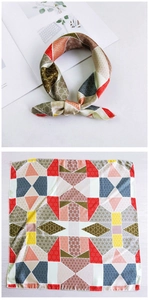 Detail view of square silk scarf showing vibrant geometric patterns and knotted styling