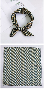 Detail of green and yellow geometric silk scarf tied and laid flat on a white surface