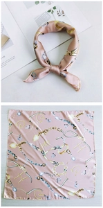 Pink silk square scarf with gold chain and jewelry patterns in a workspace setting