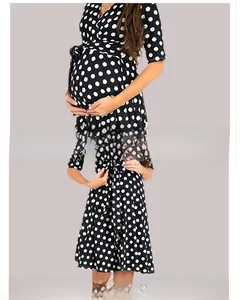Detalle de vestido de maternidad negro con lunares blancos, cuello en V y lazo en cintura