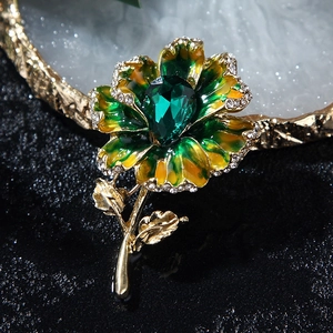 Detailed macro view of a floral brooch featuring green enamel petals and a pear-cut gemstone