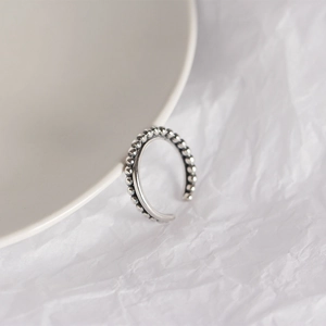 Detail of S925 sterling silver beaded cross ring on white ceramic plate background
